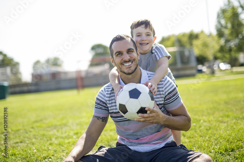 man with child playing football on field