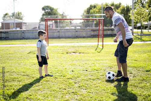 man with child playing football on field