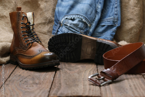 Men's shoes, jeans, leather belt on a background of wooden plank
