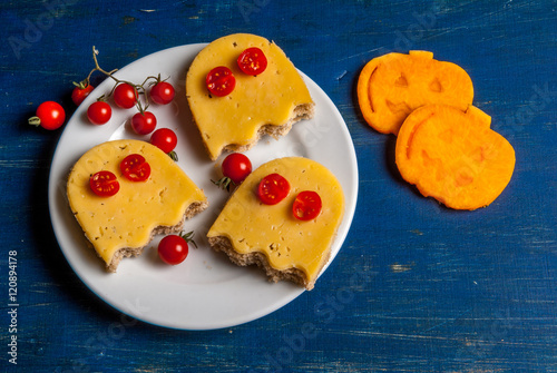 Funny food for a child for Halloween: the sandwiches in the shape of ghosts and slices of fresh pumpkin, carved cookie cutters in the form of a pumpkin photo