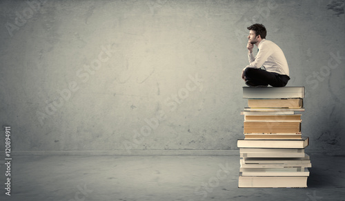 Obraz na plátně Student sitting on stack of books