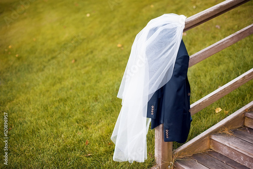veil of the bride and groom's jacket on wooden stairs