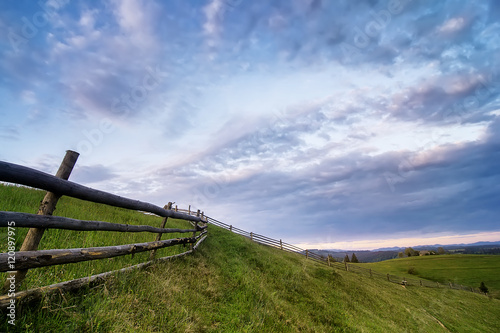 rural wooden fence. natural summer landscape with blue cloudy sky