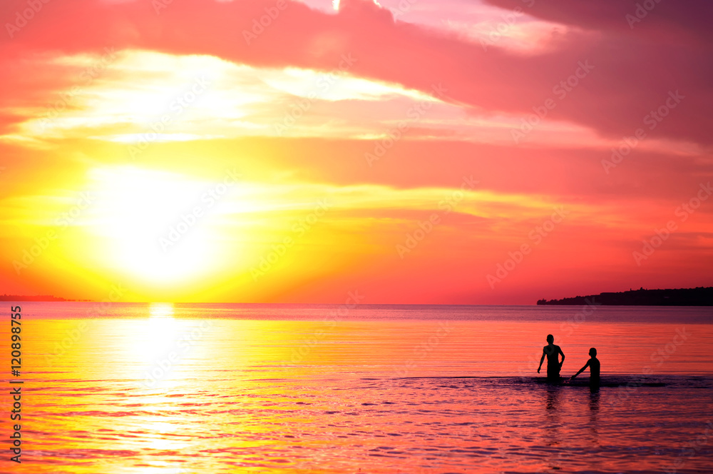 Two  men swiming  in the ocean at sunset. natural summer background
