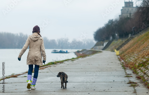 Teenage girl walking dog on cloudy autumn day. photo