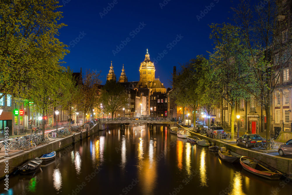 St.Nicolas church and canals at night in Amsterdam, Netherlands.