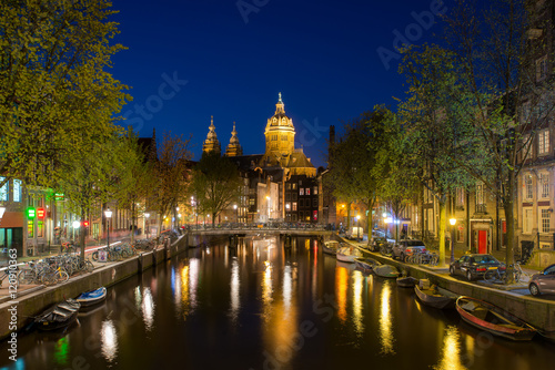 St.Nicolas church and canals at night in Amsterdam, Netherlands.
