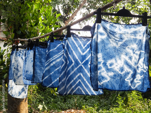 Beautiful natural indigo tie dye fabric with garden view in background. photo