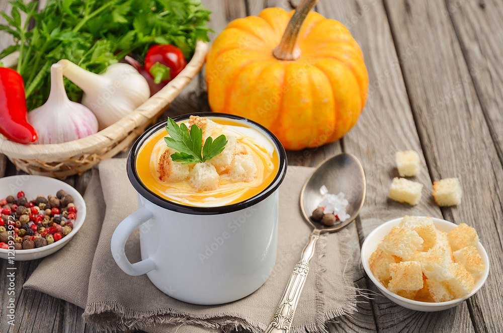 Pumpkin soup with cream and parsley in a mug on wooden background, selective focus Pumpkin soup with cream and parsley in a mug on wooden background, selective focus