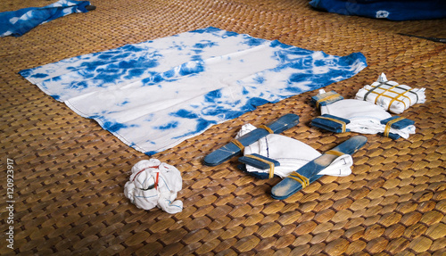 Natural indigo tie dye equipment on rattan mat.