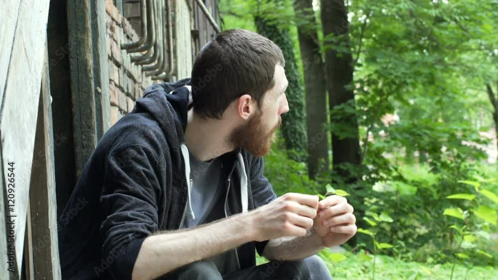 Man sitting next to the abandoned building and smelling weed
Man sitting next to the abandoned building and smelling weed
