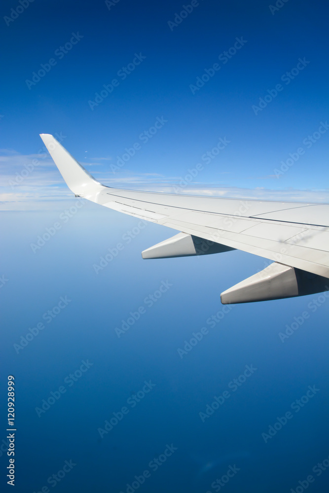 Airplane wing during flight over the blue sky Airplane wing during flight over the blue sky