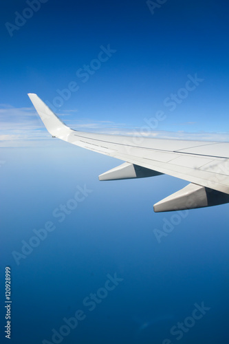 Airplane wing during flight over the blue sky