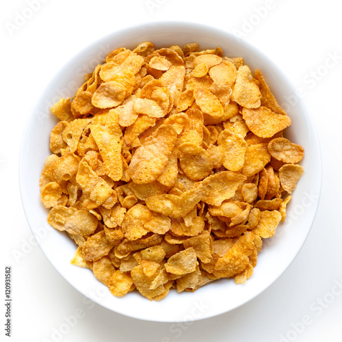 Bowl of dry cornflakes isolated on white from above.