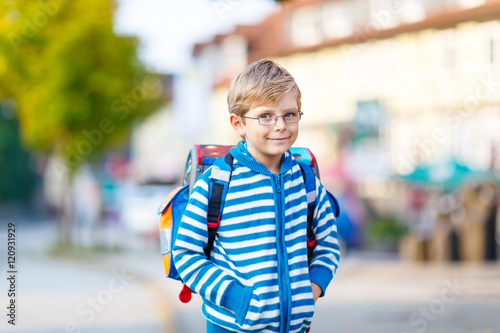little kid boy with school satchel on way to school 