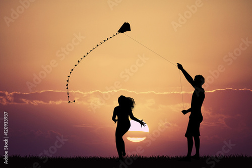 man and girl with kite at sunset