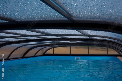 Outdoor swimming pool with roof construction and wet drops on it