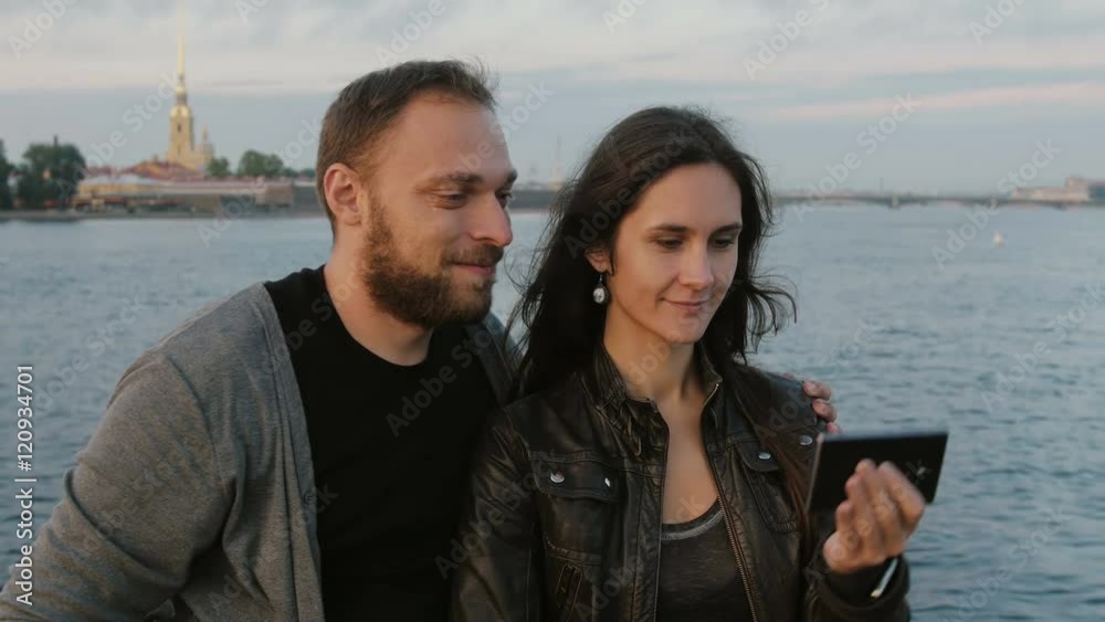 Beautiful young couple taking selfie on the background of river and the city. Peter and Paul Fortress, St. Petersburg 4K Beautiful young couple taking selfie on the background of river and the city. Peter and Paul Fortress, St. Petersburg 4K