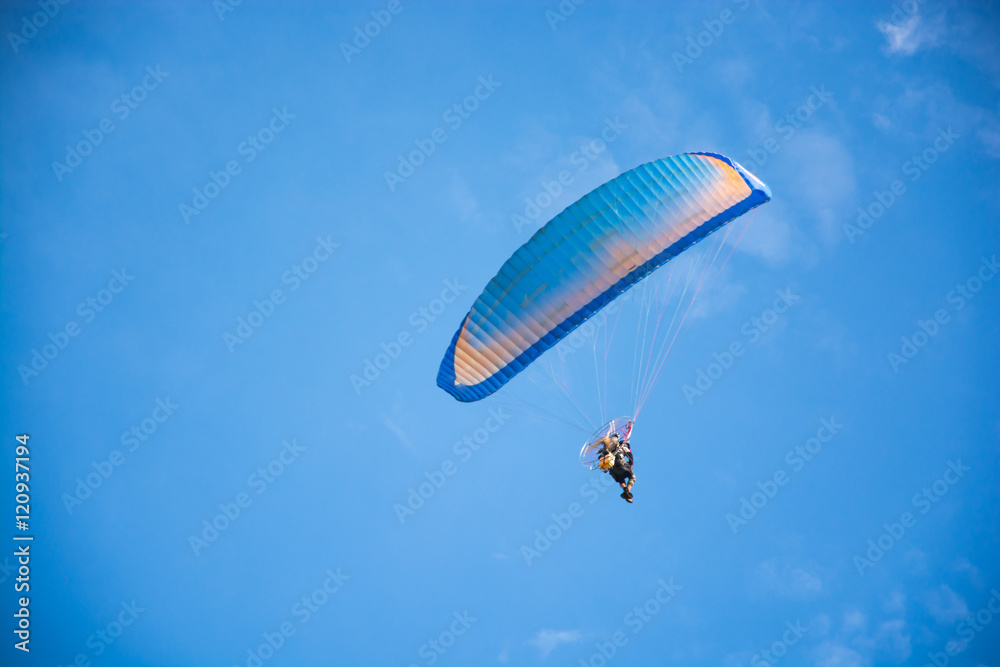 paramotor flying against blue sky paramotor flying against blue sky