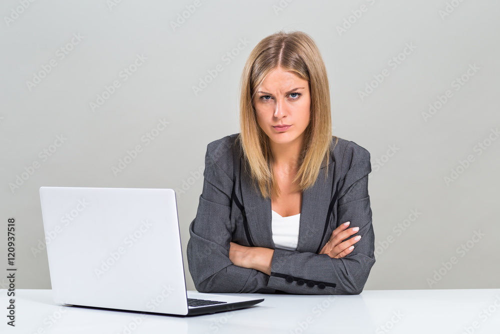 Portrait of very angry businesswoman with laptop sitting at the table.
Portrait of very angry businesswoman with laptop sitting at the table.