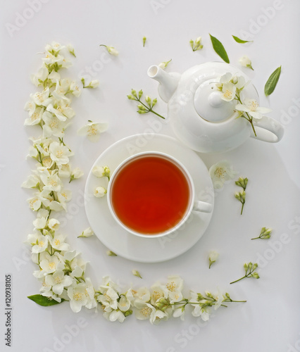 Cup of tea with jasmine flowers on white background