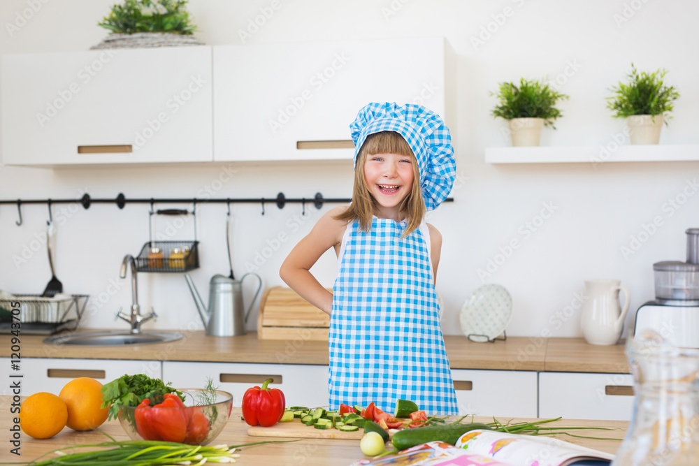 Pretty little girl in cook clothes smiles on a kitchen Pretty little girl in cook clothes smiles on a kitchen