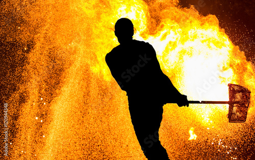Canvastavla Fireshow performance. Silhouette of man with hammer, fire around
