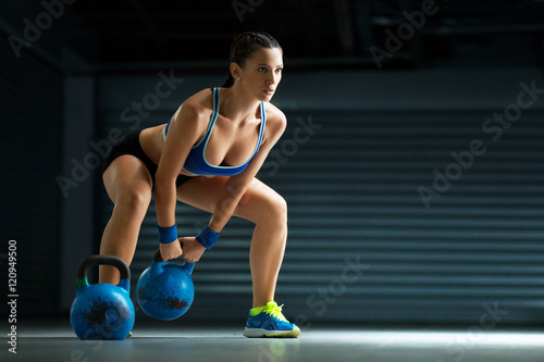 Young fit woman has cross fit training by kettle bell.