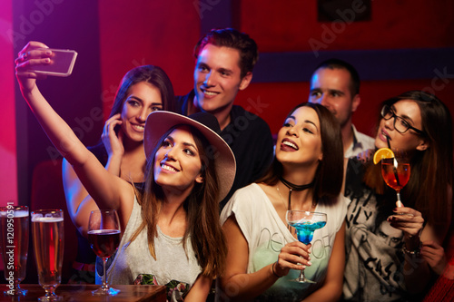 Group of young smiling people taking selfie in the club or bar