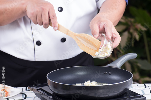 Chef putting garlic to the pan