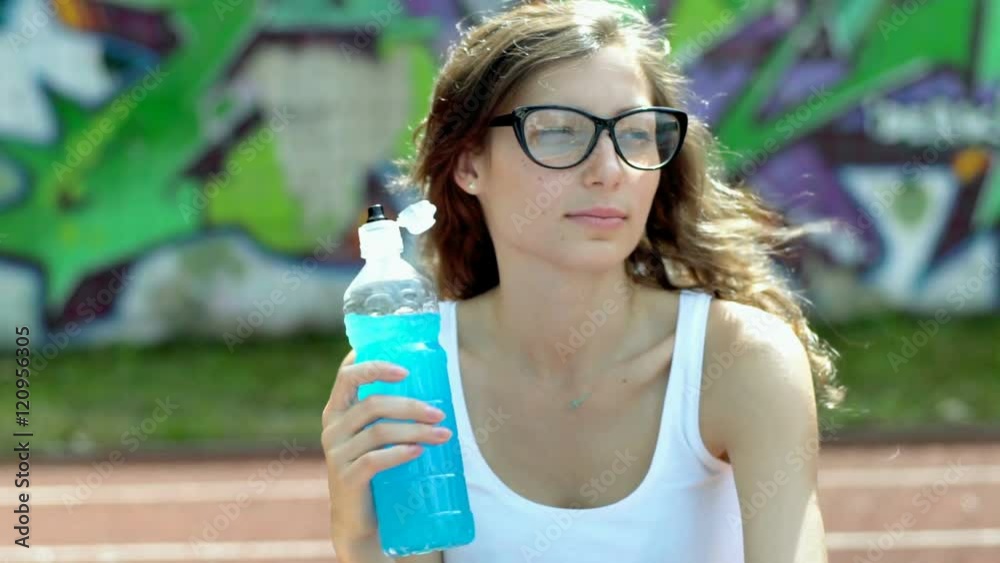 Thoughtful girl sitting on sports field and drinking energy drink
Thoughtful girl sitting on sports field and drinking energy drink