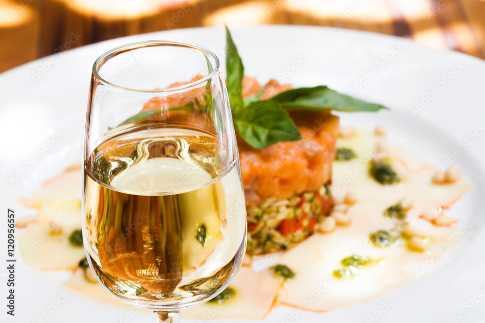 Glass of sherry jerez, pink salmon fish tartar plate background, soft focus photo
