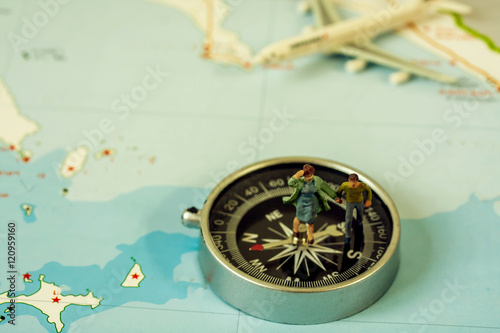 selective focus of miniature tourist on compass over map with plastic toy airplane,abstract background to travel concept 