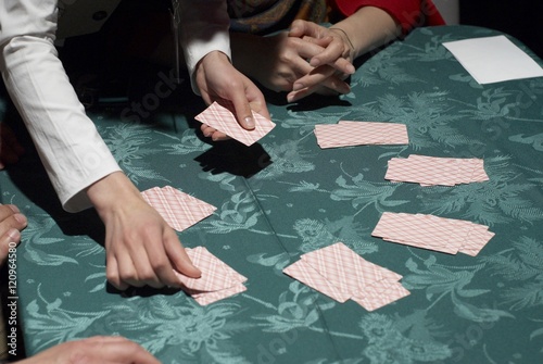 Obraz na plátně Croupier dealing cards in a poker game placing them face up on the green baize o