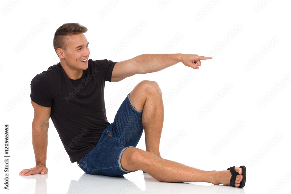 Handsome Young Man Sitting On Floor And Pointing Handsome Young Man Sitting On Floor And Pointing