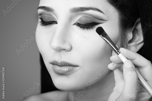 Makeup artist applying eye shadow. Black and white