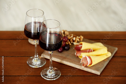 Glasses with red wine and tasty snacks on wooden table
