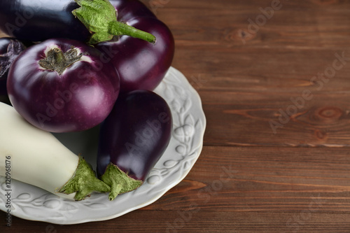 Plate with aubergines on wooden background