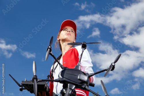 A woman is standing and holding drone over sky