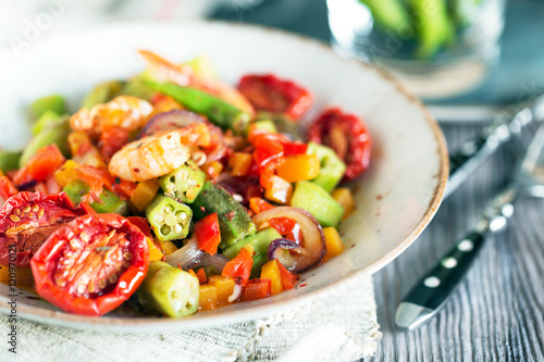 Vegetable stew with okra and shrimps in rustic composition – close up view