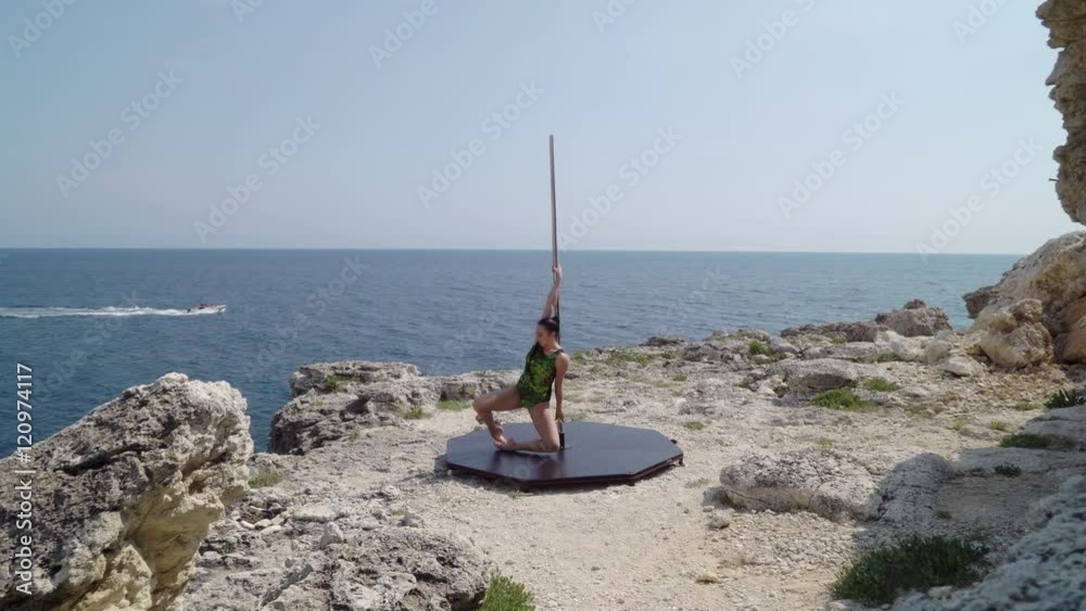 Strong woman dancing on portable dance and fitness pole above the sea Strong woman dancing on portable dance and fitness pole above the sea