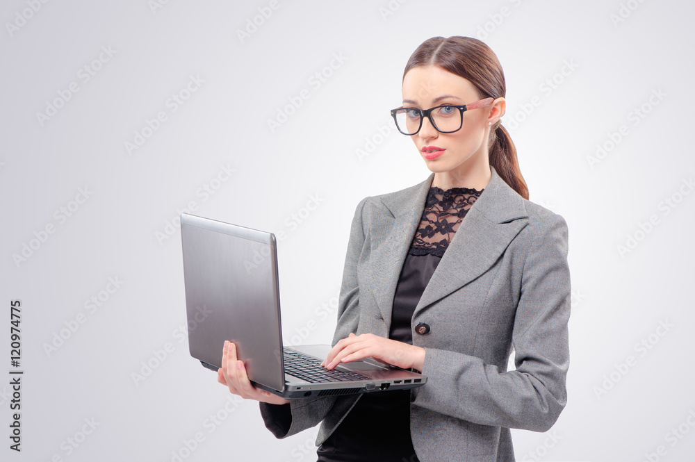 Join a digital age! Beautiful young woman in formalwear working on laptop, isolated on gray background Join a digital age! Beautiful young woman in formalwear working on laptop, isolated on gray background
