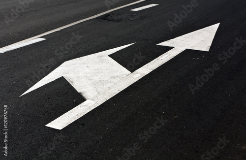 Left and straight arrow on asphalt.