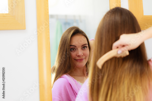 Woman combing her long hair in bathroom