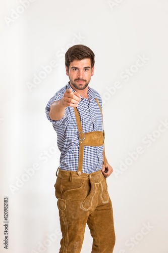Junger Mann in Lederhose zeigt mit dem Finger