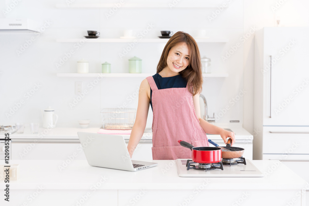 パソコンを見ながら料理をする女性 パソコンを見ながら料理をする女性