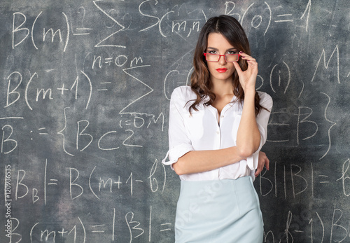 young smart sexy woman in eyeglasses near blackboard with math calculations