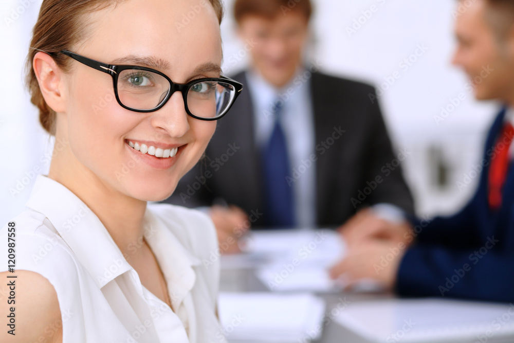 Portrait of a young business woman against a group of business people at a meeting. Portrait of a young business woman against a group of business people at a meeting.