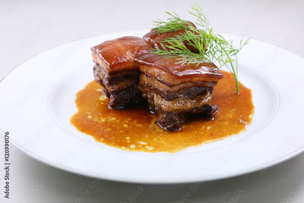 Braised pork meat in Chinese style with herbs on white plate Braised pork meat in Chinese style with herbs on white plate