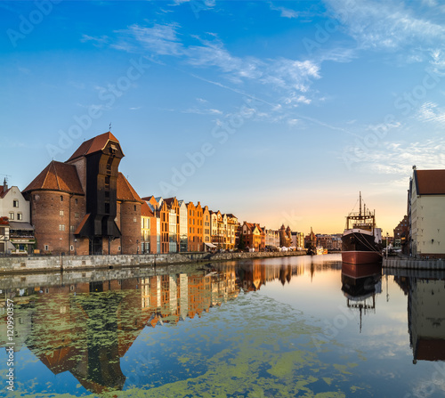 Waterfront of Gdansk with reflection early in the morning, panorama image. Focus on the large black warf building on the left and large ship on the right.